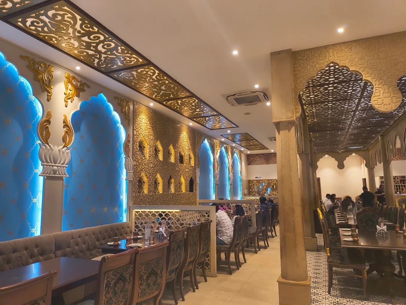 Dining hall with glowing blue arches and gold lattice work